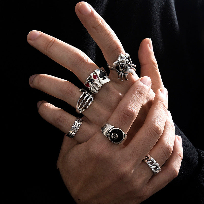 Hand wearing multiple silver rings with various designs on a black background