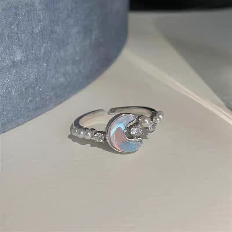 Silver ring with moon and star design on a light surface