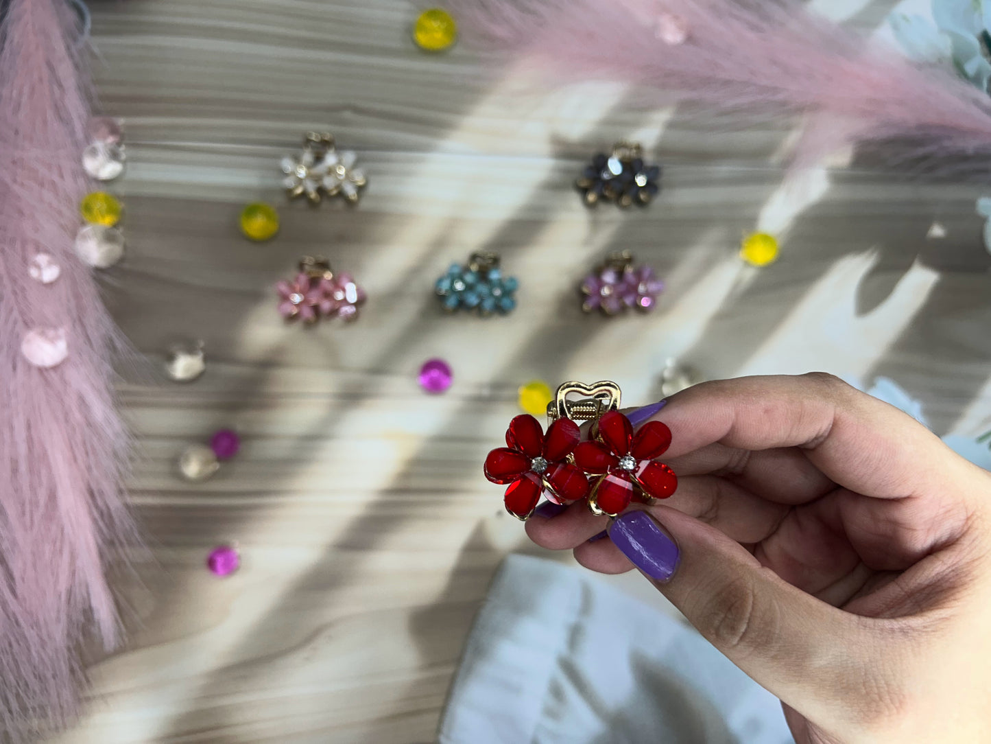 Hand holding a red decorative hair clip with a blurred background of similar clips.