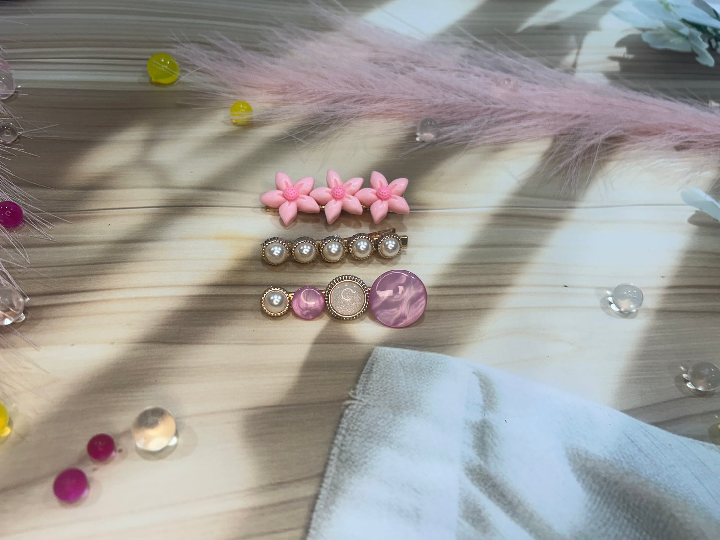 Set of decorative hair pins on a wooden surface with feathers and small stones.