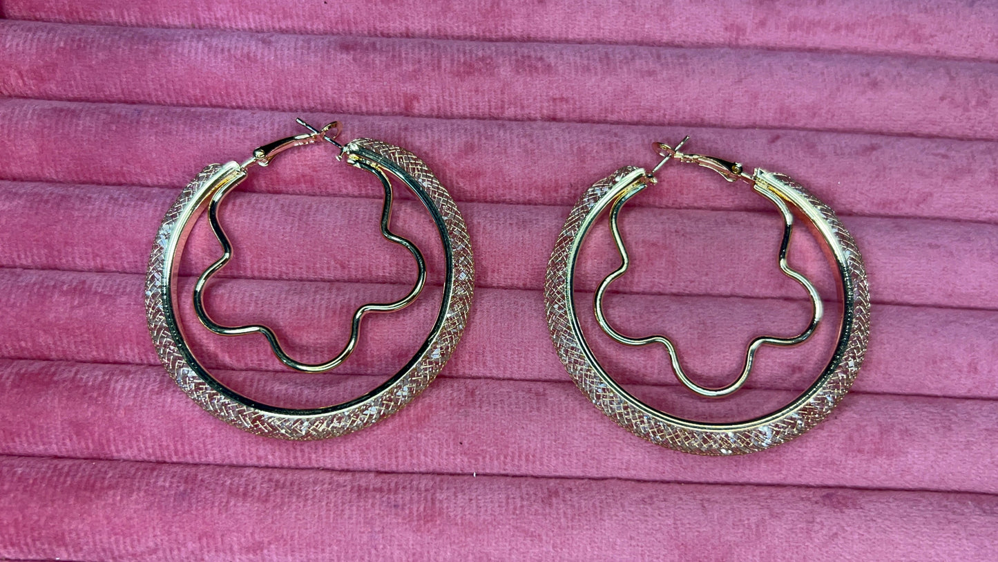 Gold hoop earrings on a pink textured background