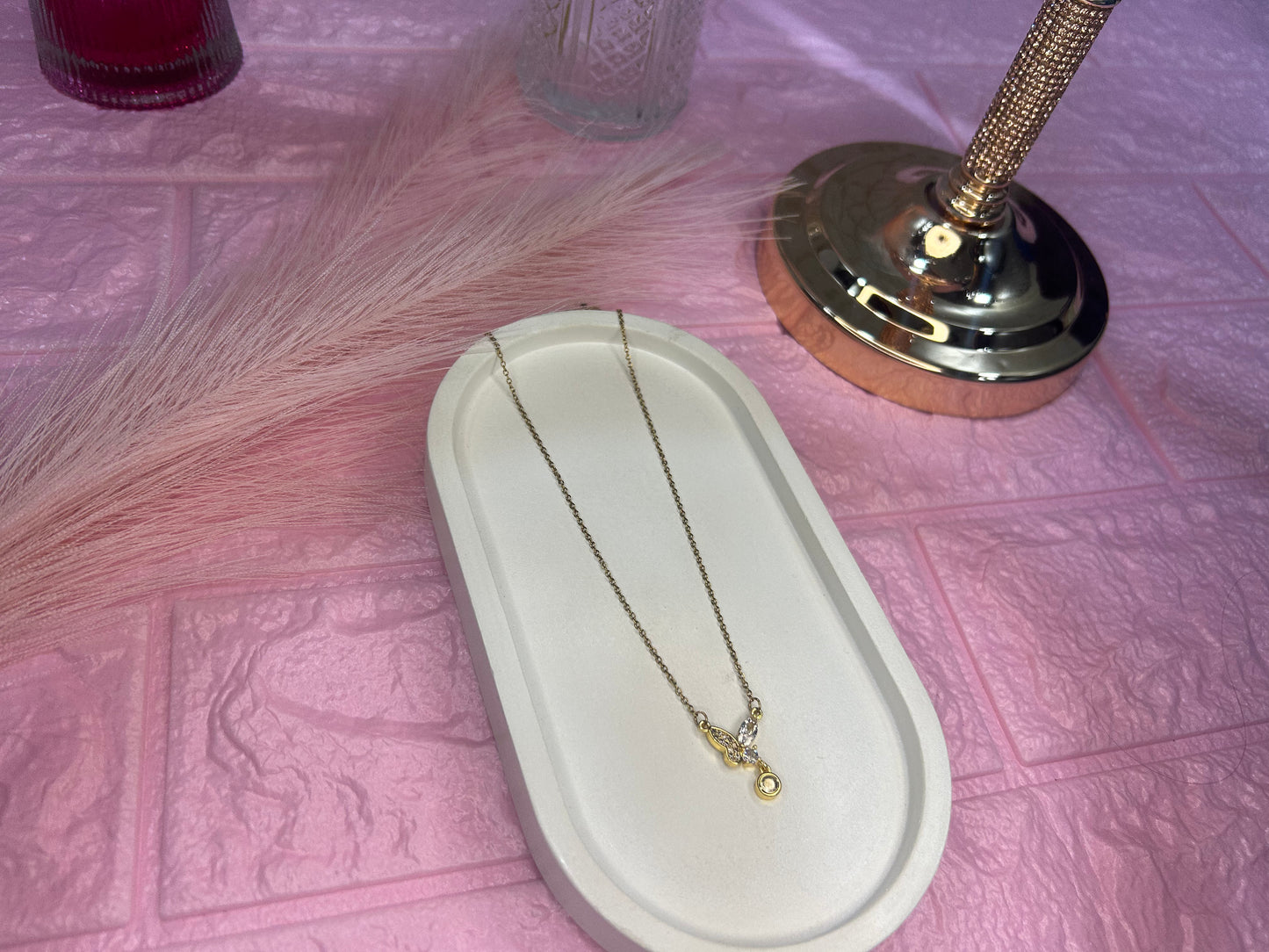 Necklace on a white dish with a pink textured background