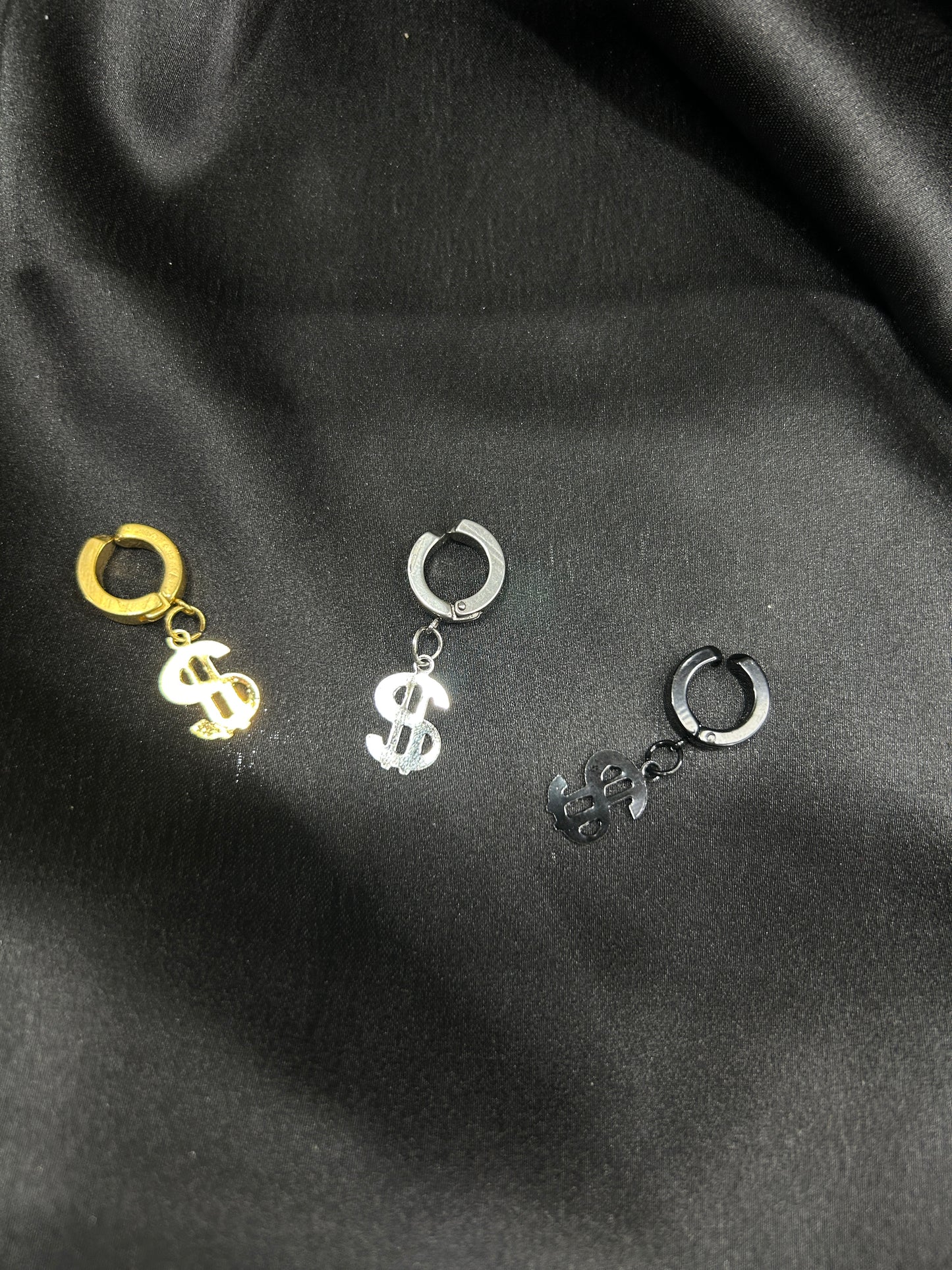 Three pairs of earrings on a black fabric background