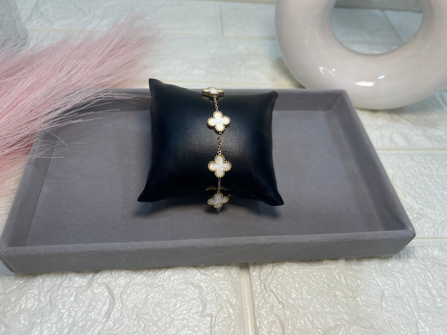 Silver bracelet with floral design on a black pillow on a gray tray.