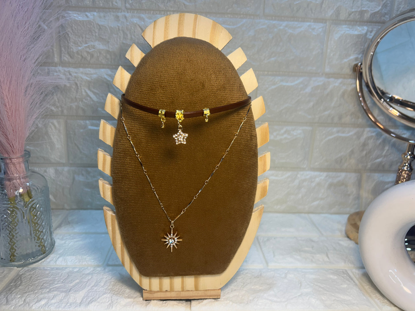 Jewelry display with necklaces and earrings on a wooden stand against a tiled wall.