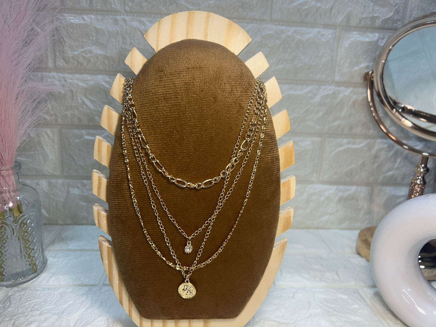 Necklace displayed on a brown velvet stand with a marble wall background