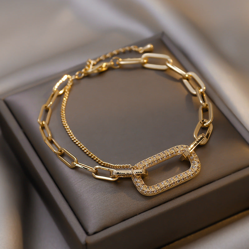 Gold chain bracelet with a clasp on a brown jewelry box