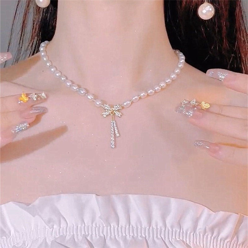Pearl necklace with a small pendant worn by a person, with close-up of jewelry on hands.