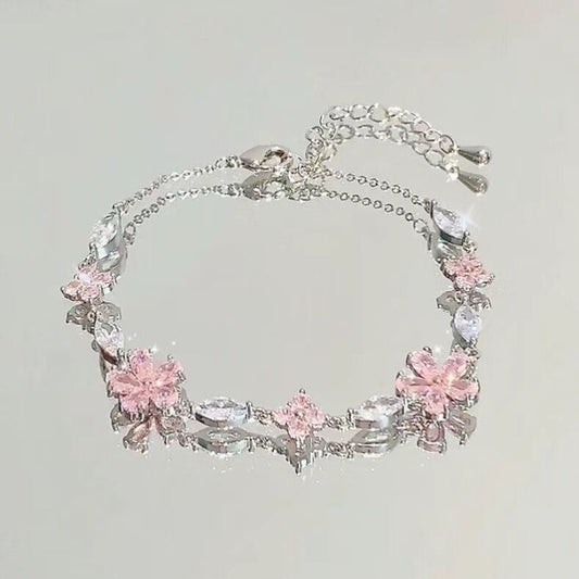 Silver bracelet with pink floral charms on a light gray background