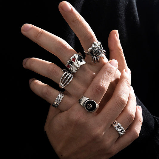 Hand wearing multiple silver rings with various designs on a black background
