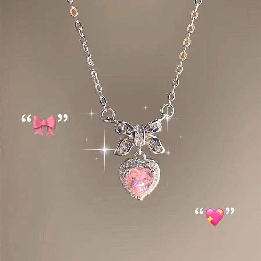 Necklace with butterfly and heart-shaped pink gemstone pendant on a soft brown background