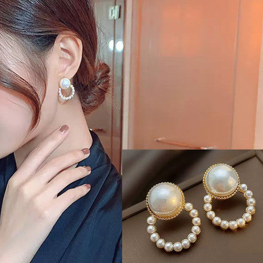 Pearl earrings worn by a person with a close-up of the earrings on a reflective surface.