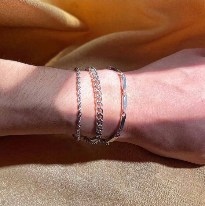 Close-up of a wrist wearing multiple bracelets on an orange fabric background