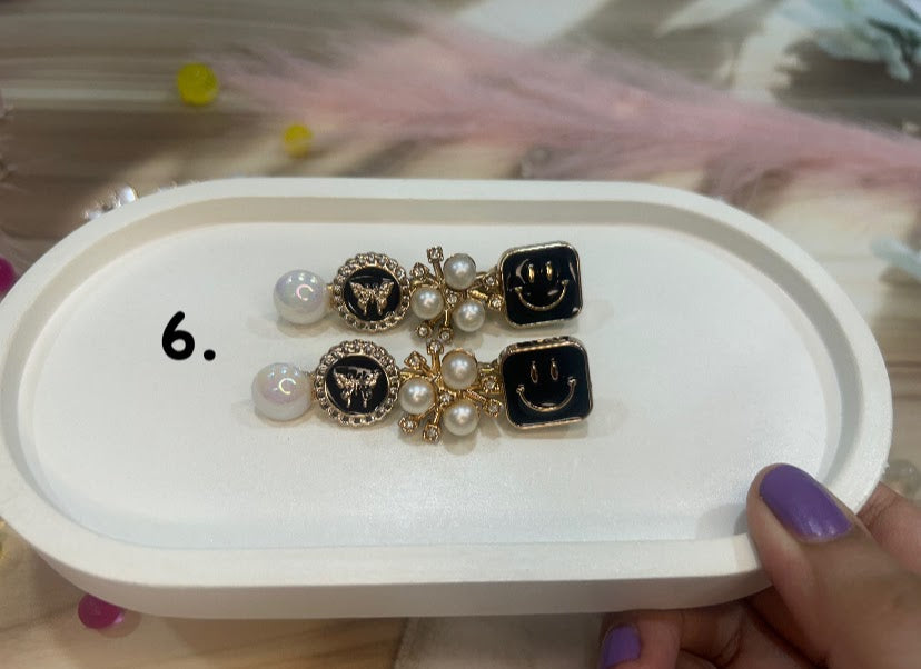 Pair of hair clip with pearl-like beads and gold accents on a white tray.