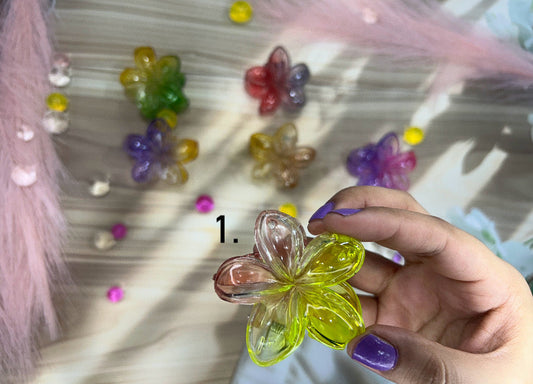 Hand holding a transparent butterfly-shaped object with colorful beads on a reflective surface.