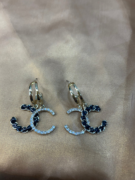 Pair of earrings with 'CC' design on a beige background