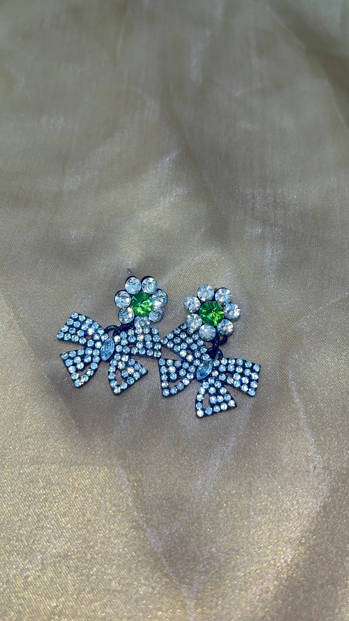 Decorative brooch with blue and green gemstones on a beige fabric background