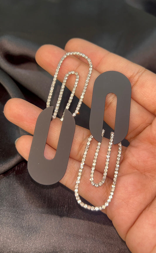 Two metallic dog tags on a chain held in a hand against a dark fabric background