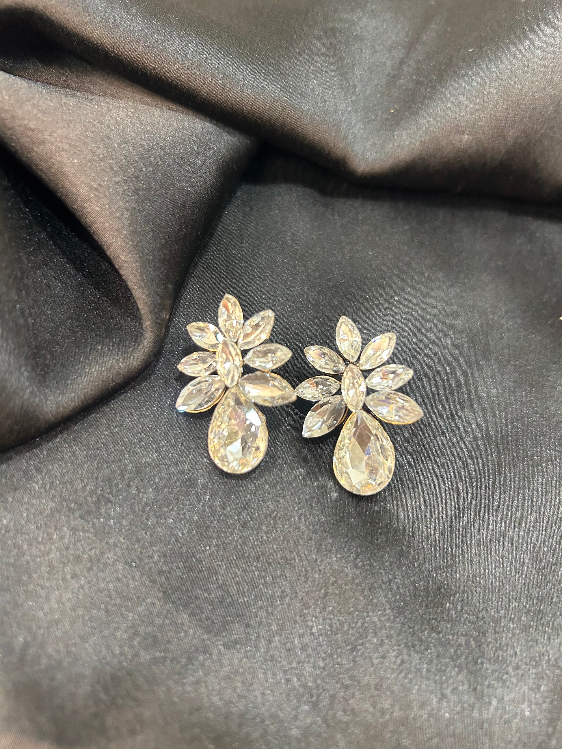 Pair of silver floral earrings on a dark fabric background