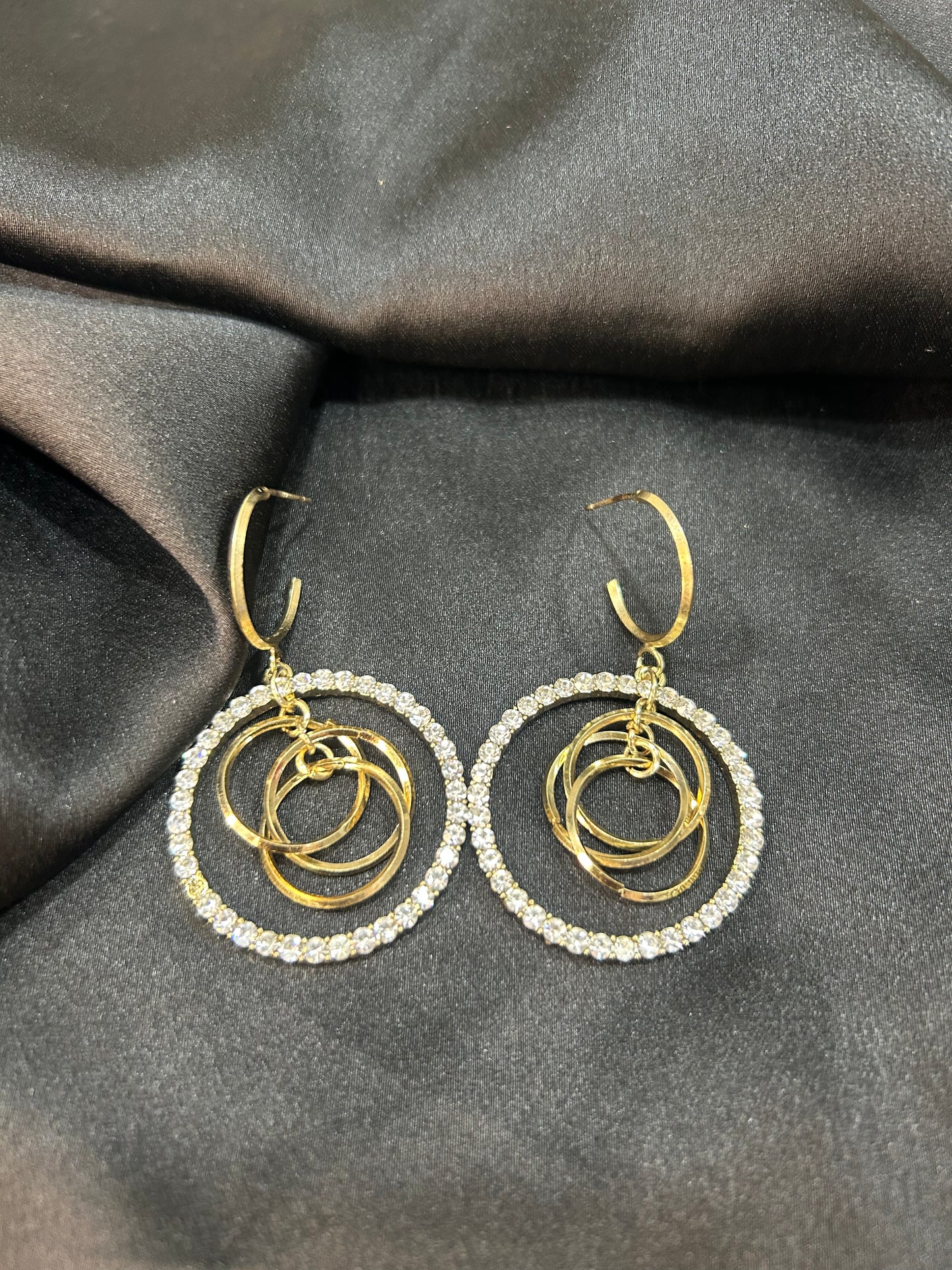Gold and silver hoop earrings on a dark fabric background