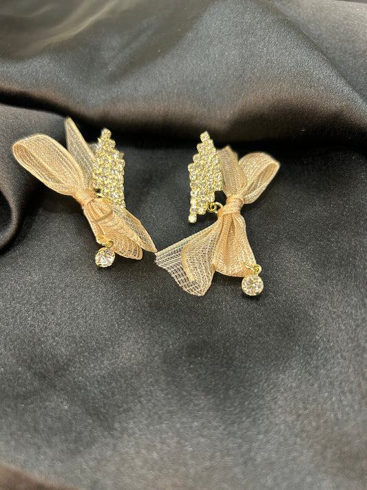 Gold earrings with intricate designs on a dark fabric background