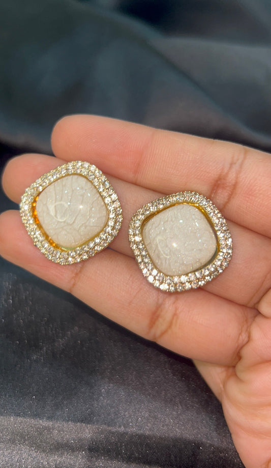 Decorative earrings held in a hand with a dark background