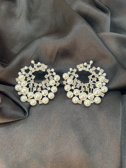Pair of pearl and crystal earrings on a dark fabric background