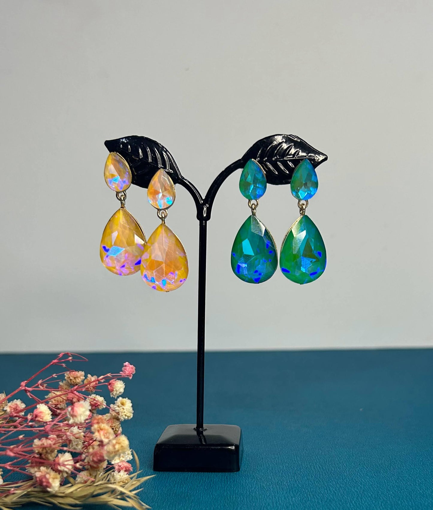 Colorful teardrop earrings on a black stand with a light gray background