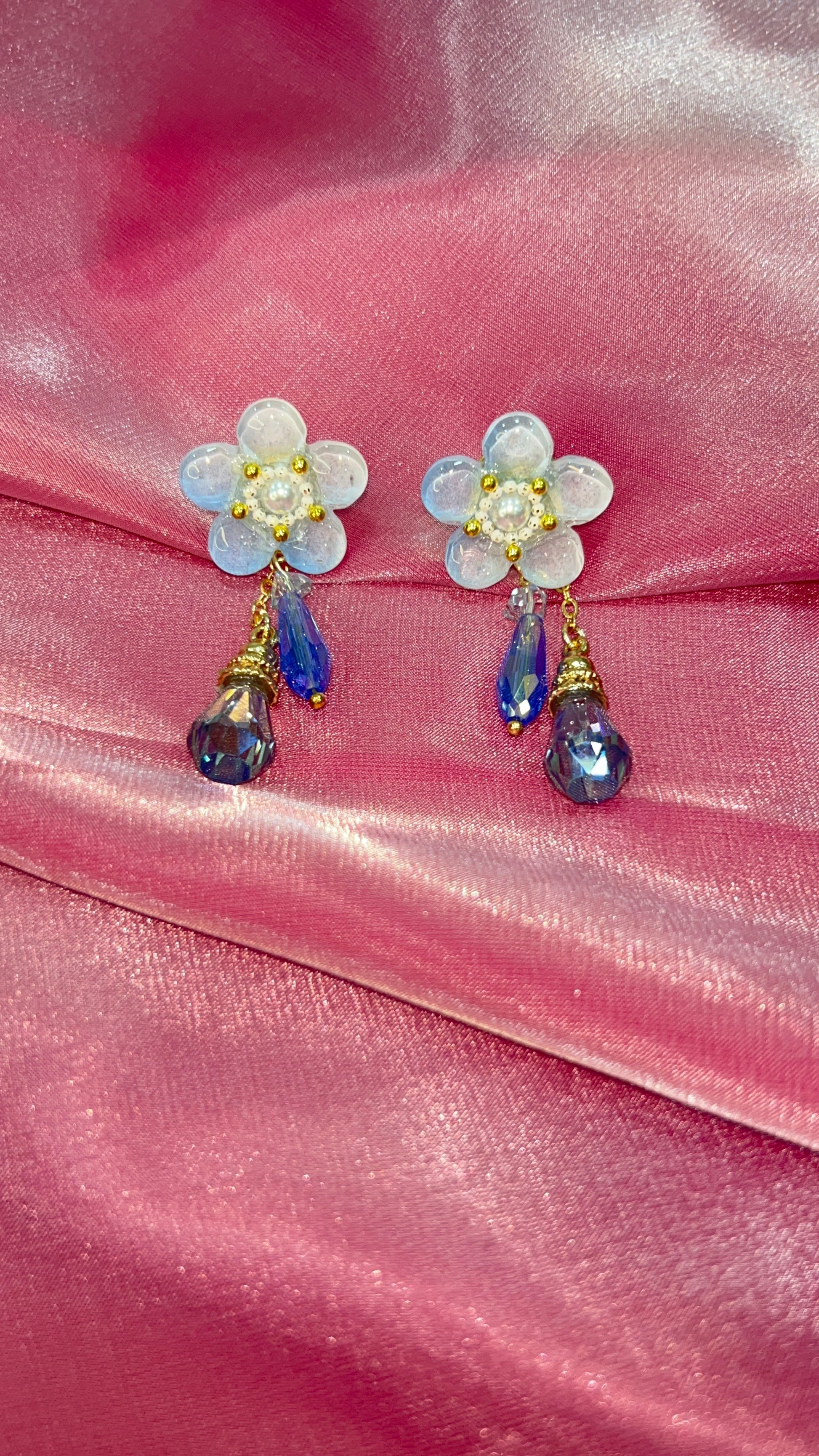 Floral earrings with gemstones on a pink satin background