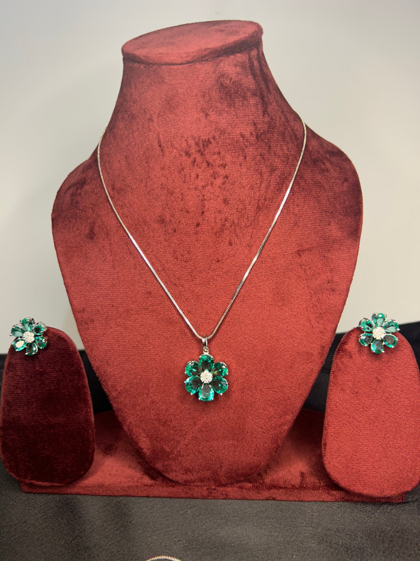 Green gemstone earrings on a pink fabric background