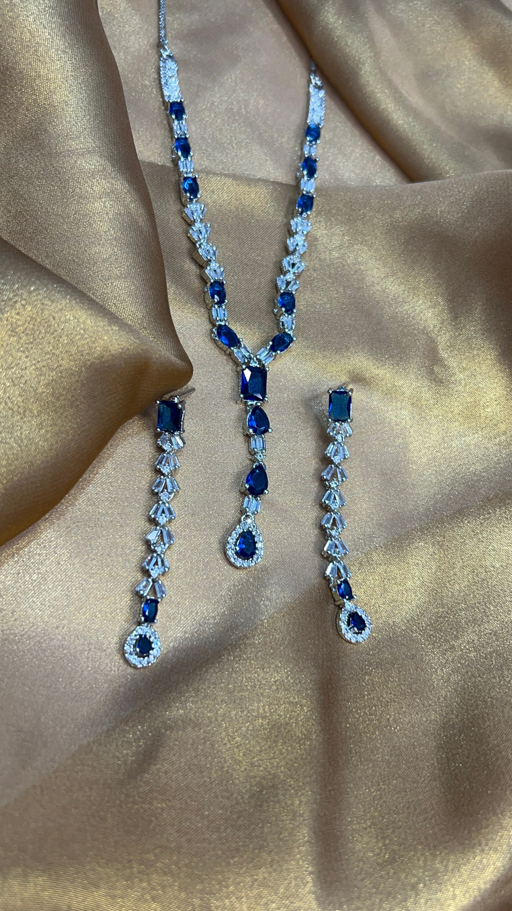 Blue gemstone necklace and earrings on a beige fabric background