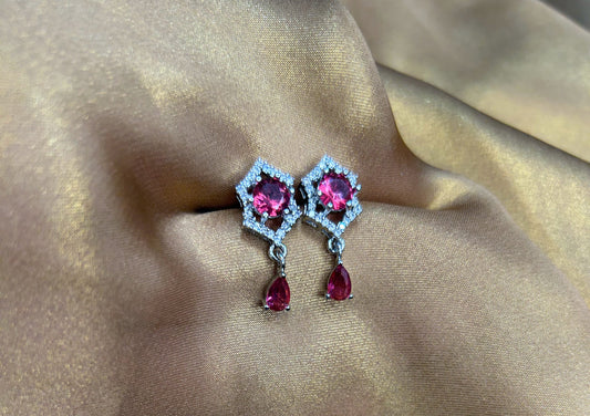 Pair of earrings with pink gemstones on a beige fabric background