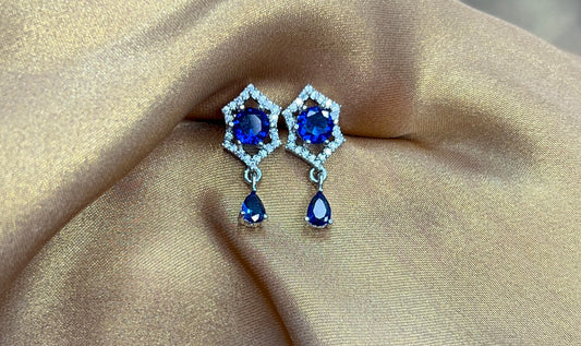 Pair of earrings with blue gemstones on a beige fabric background