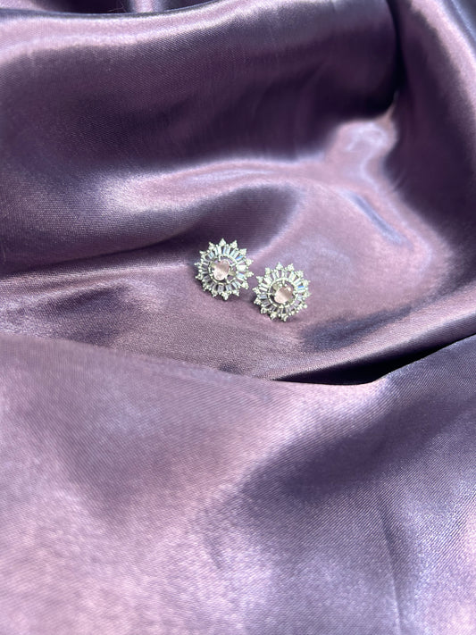 Pair of green earrings on a purple satin surface