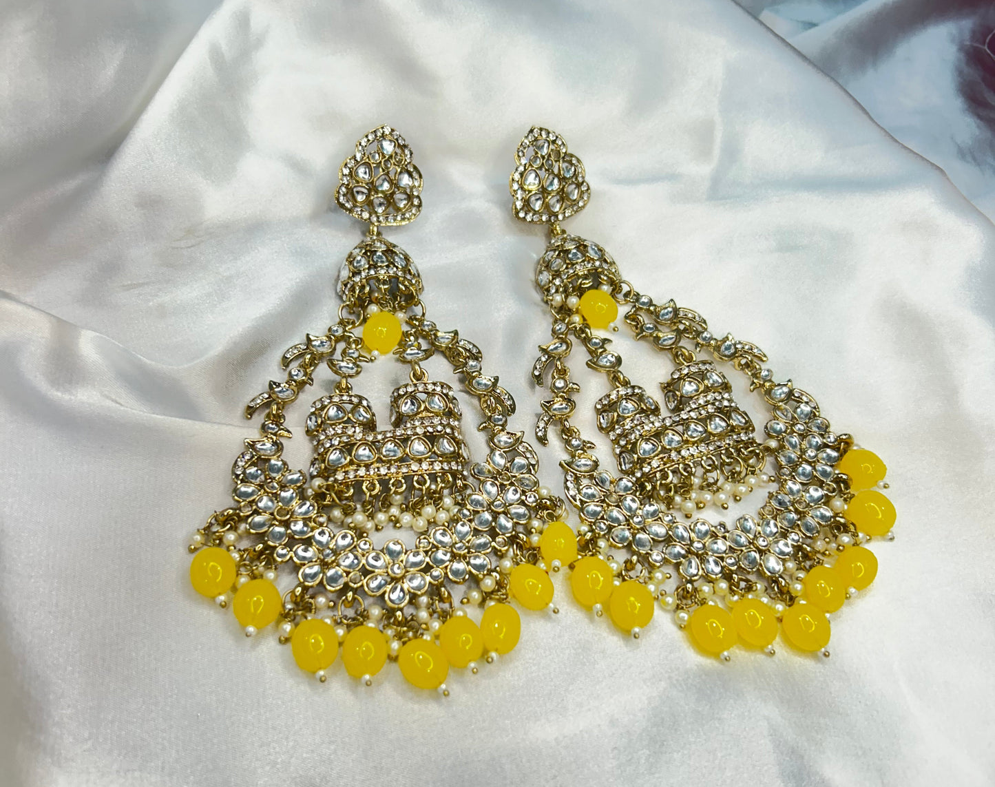 Pair of gold and yellow earrings on a white fabric background