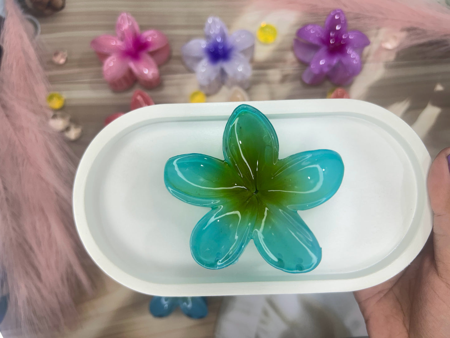 Green flower-shaped object on a white tray with colorful flowers in the background
