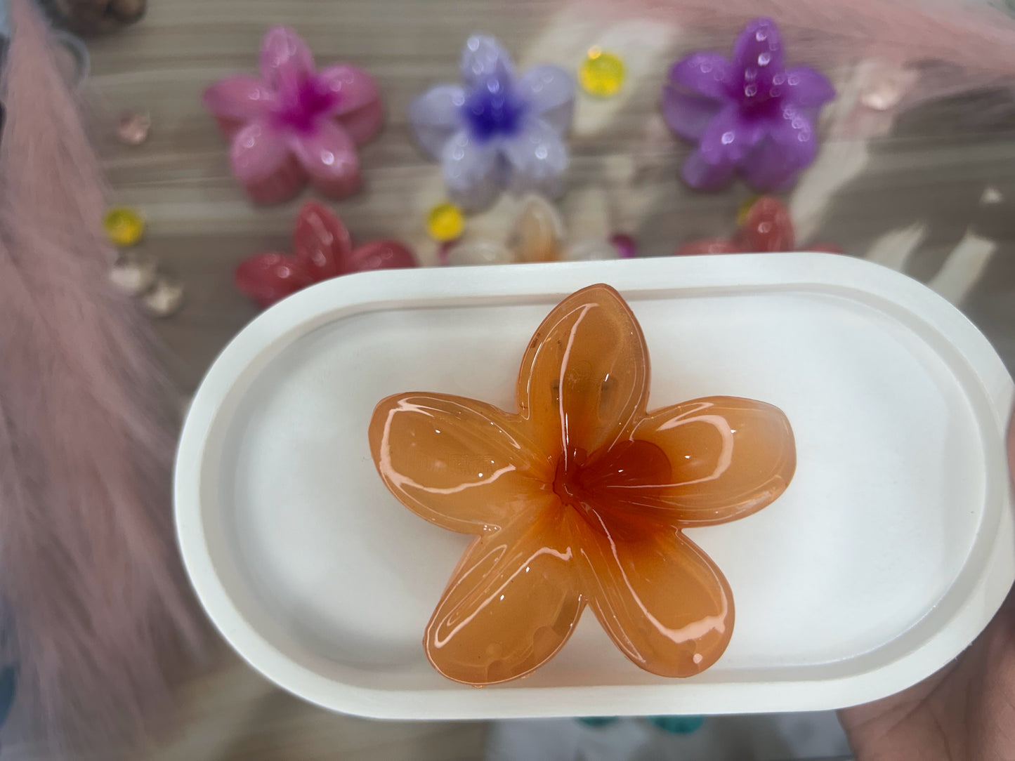 Orange flower-shaped object on a white base with colorful flowers in the background