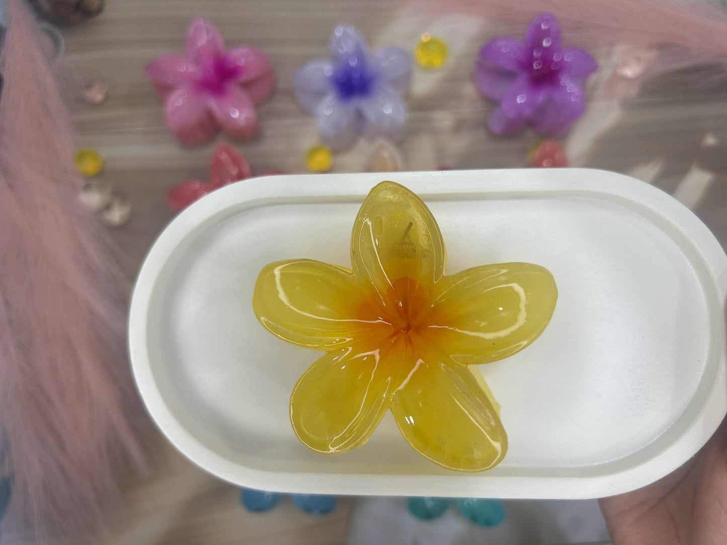 Yellow flower-shaped object on a white plate with colorful flowers in the background