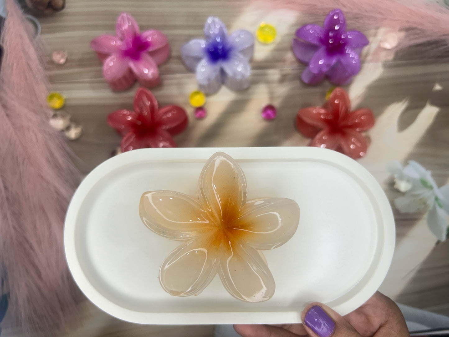 Decorative flower-shaped soap on a white tray with colorful flowers in the background