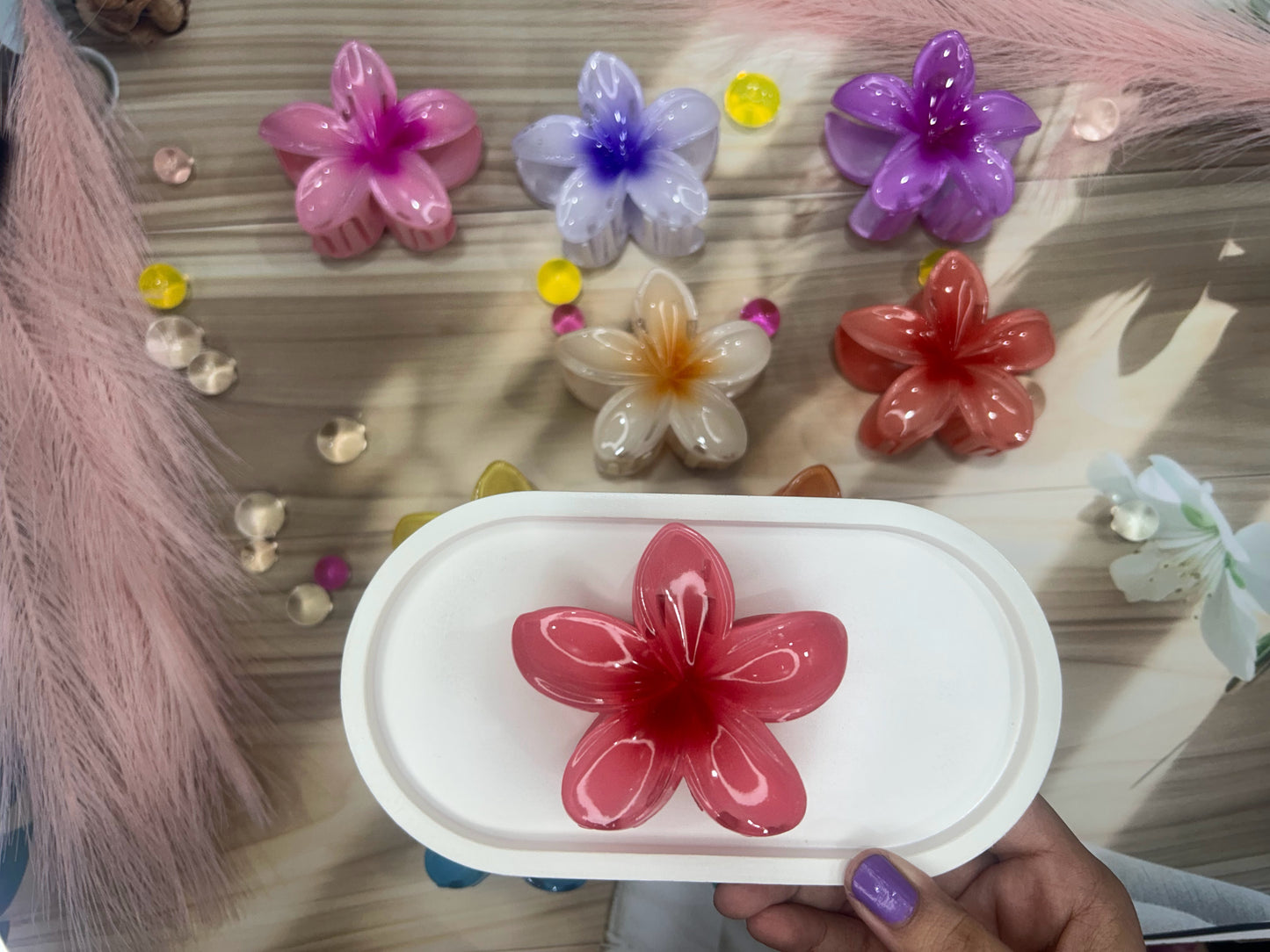 Colorful flower-shaped objects on a wooden surface with a hand holding a similar object.