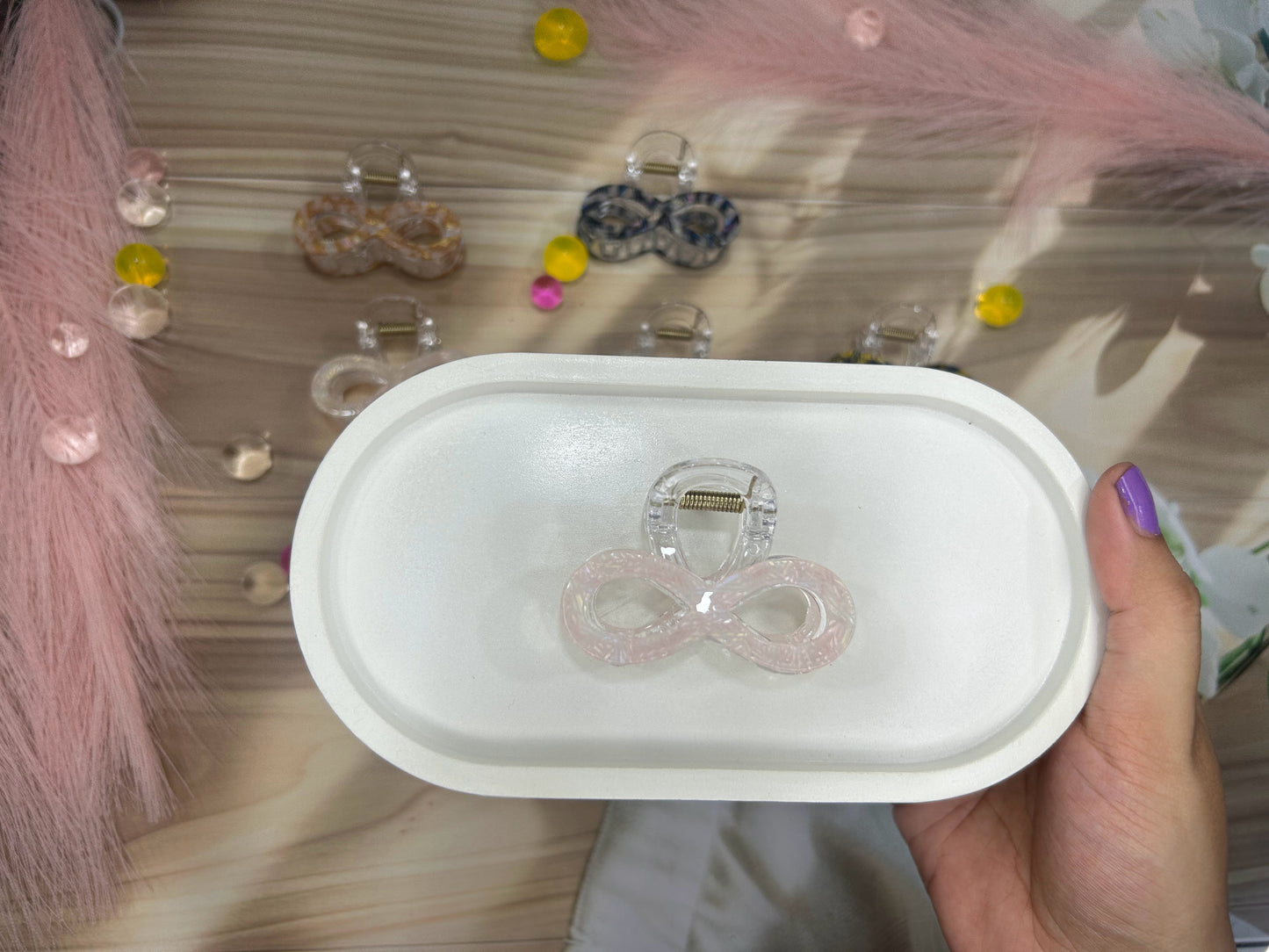 Hand holding a white container with hair ties against a decorative background