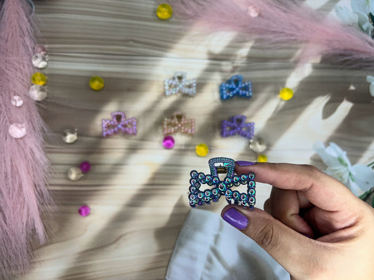 Hand holding a blue decorative bow with rhinestones against a neutral background