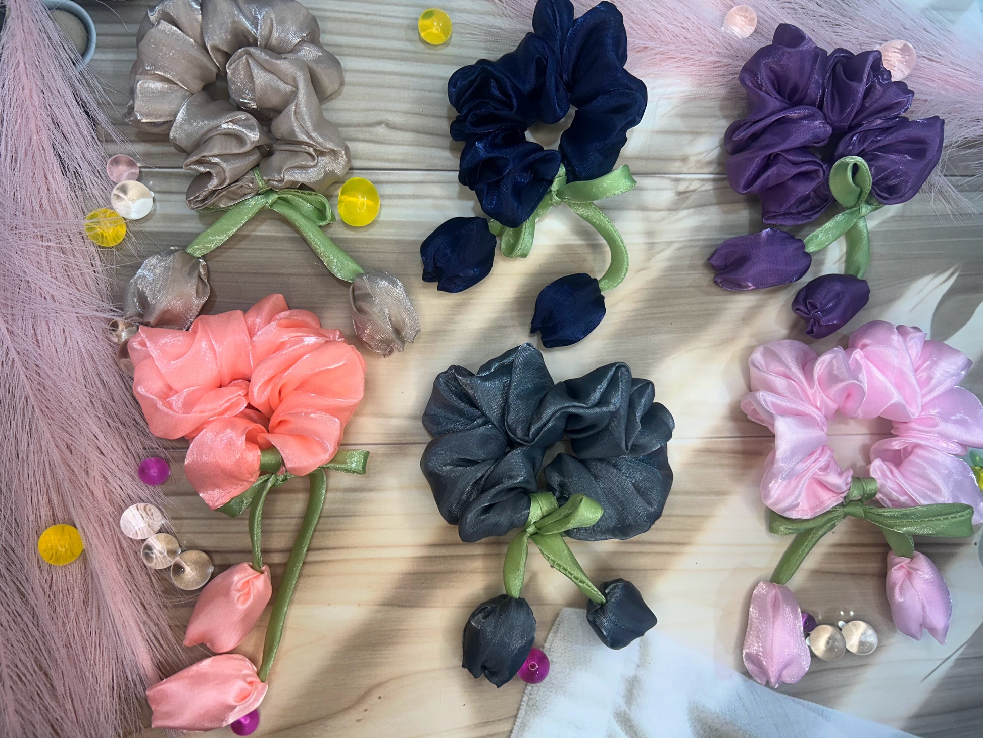 Colorful scrunchies on a wooden surface with decorative elements.