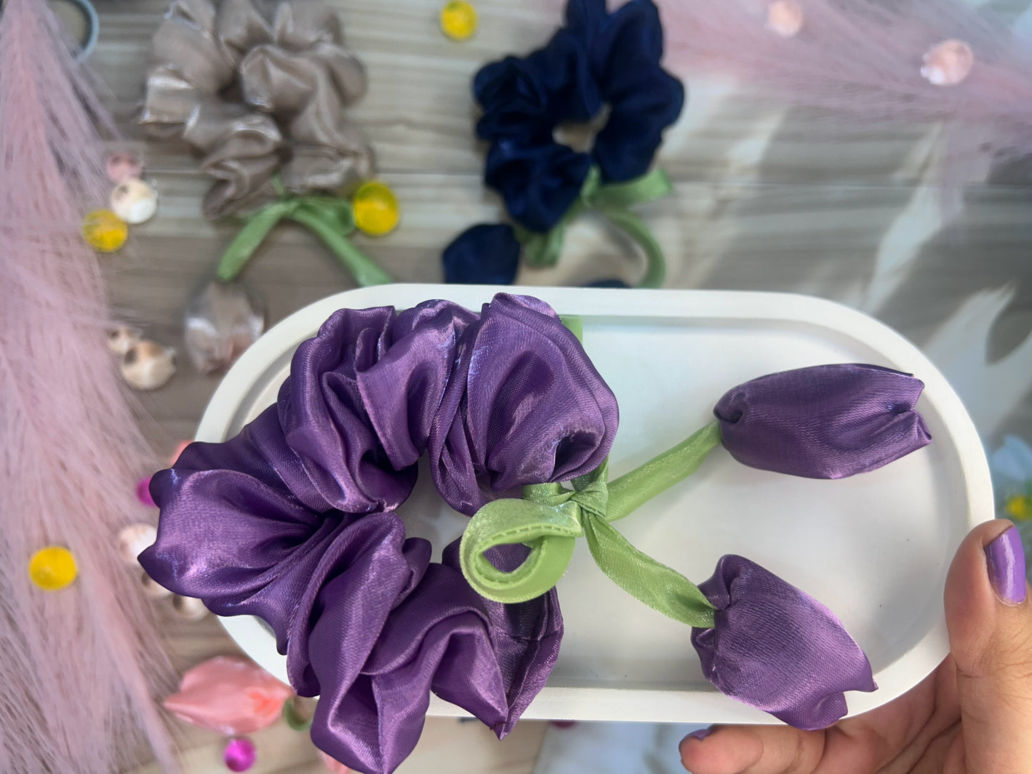 Purple scrunchie and flowers on a white plate with a blurred background