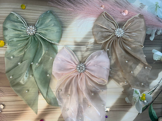 Three decorative bows with pearls on a wooden surface