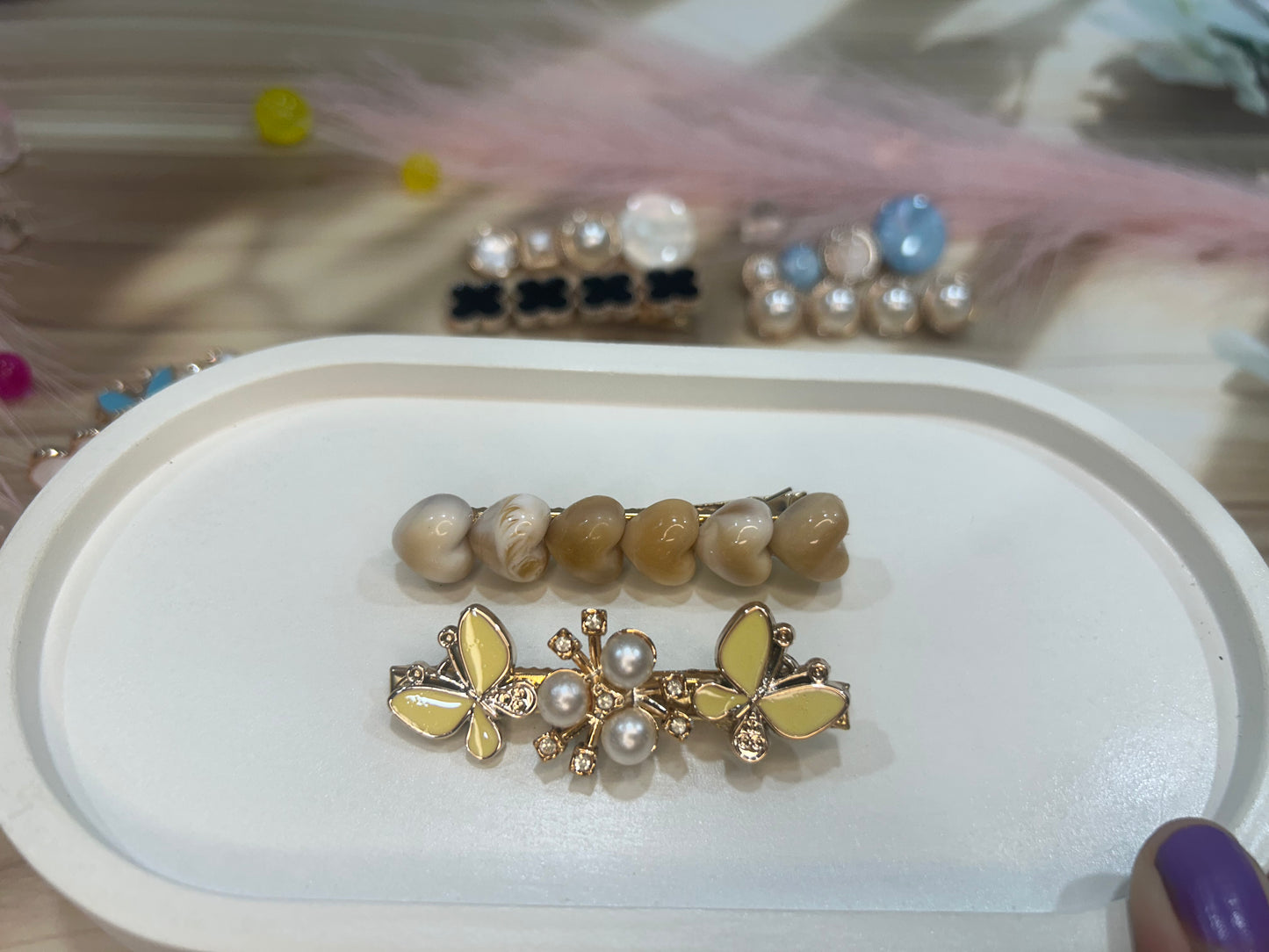 Butterfly-shaped hair clip with pearl details on a white tray