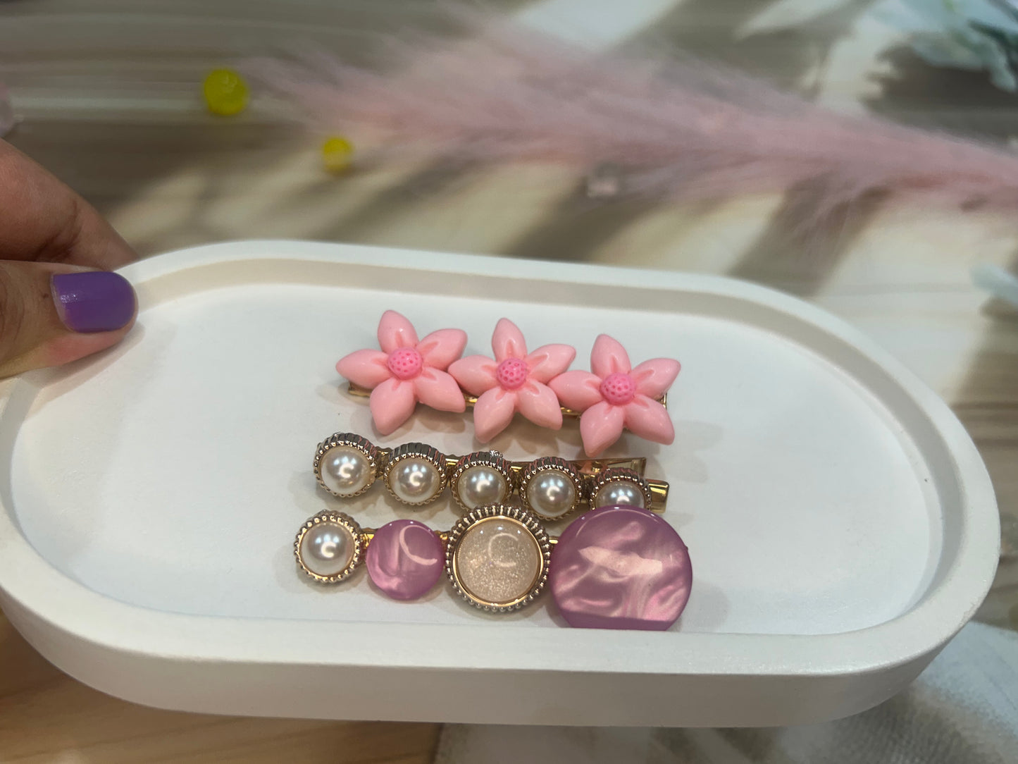 Set of decorative pins with pink flowers and pearl-like designs on a white tray.
