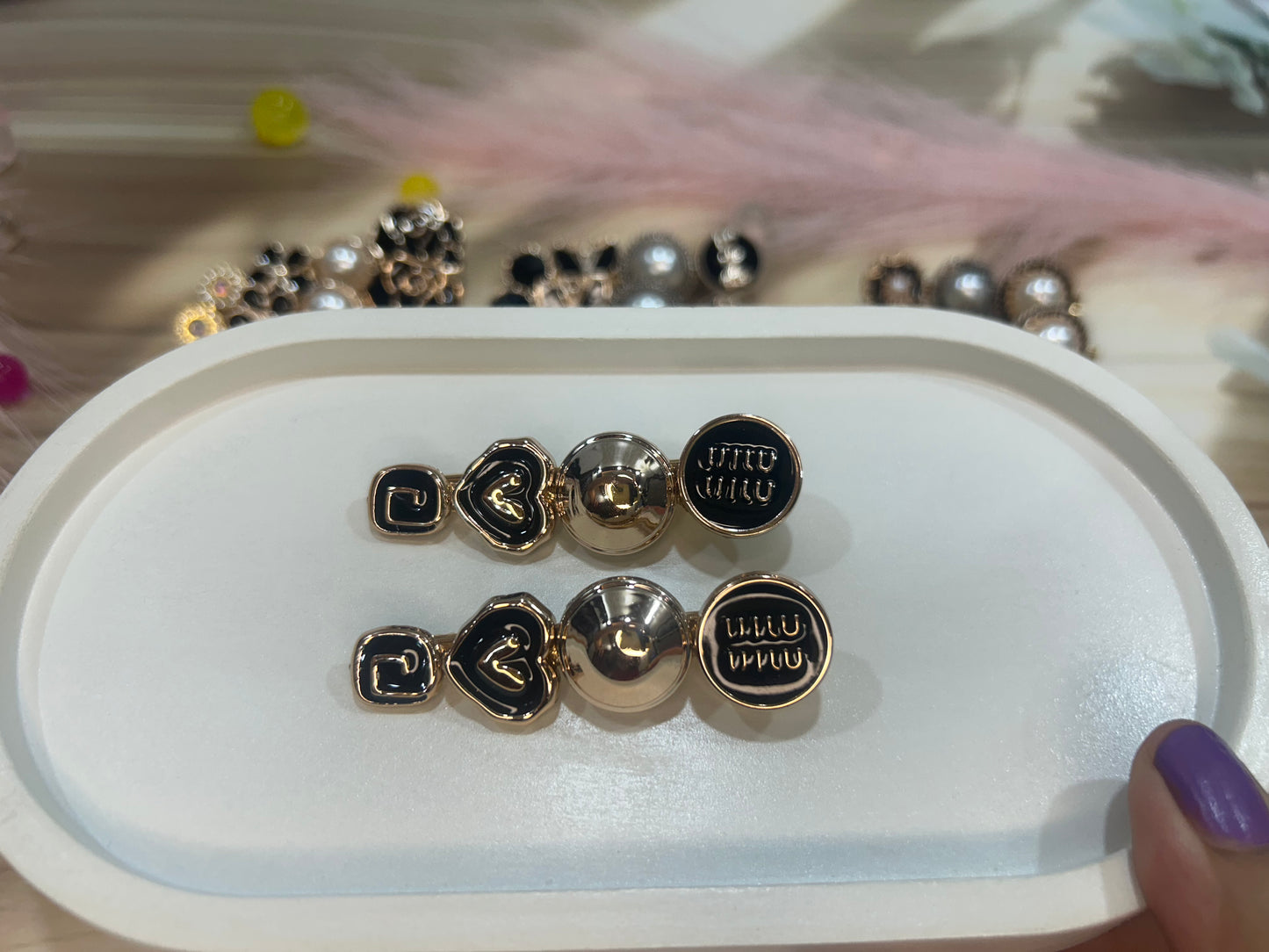 Set of hair clip with black and gold designs on a white tray.