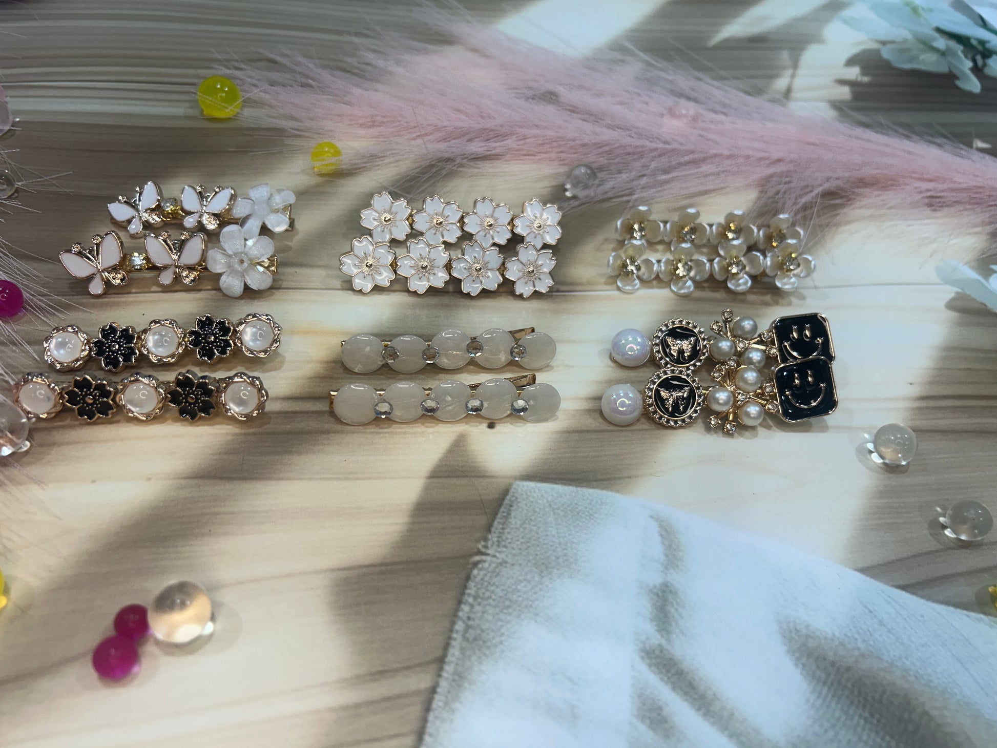Collection of decorative hair clips on a wooden surface with feathers and beads.