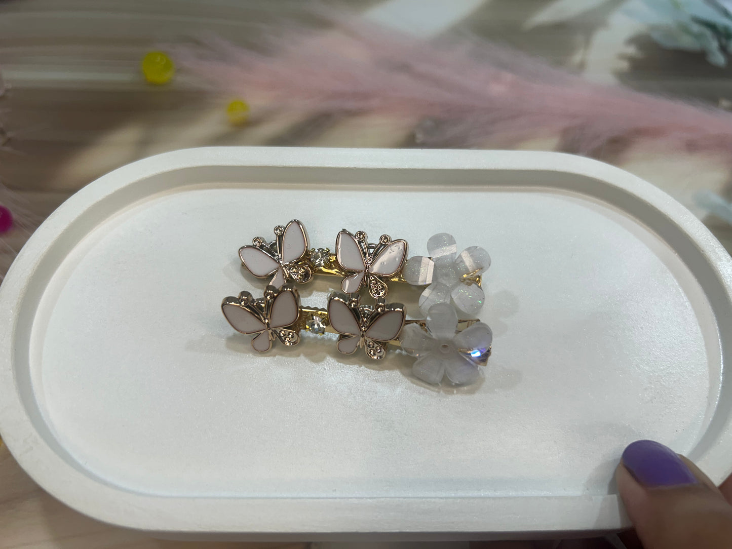 Pair of butterfly-shaped hair clip on a white display box with a blurred background.